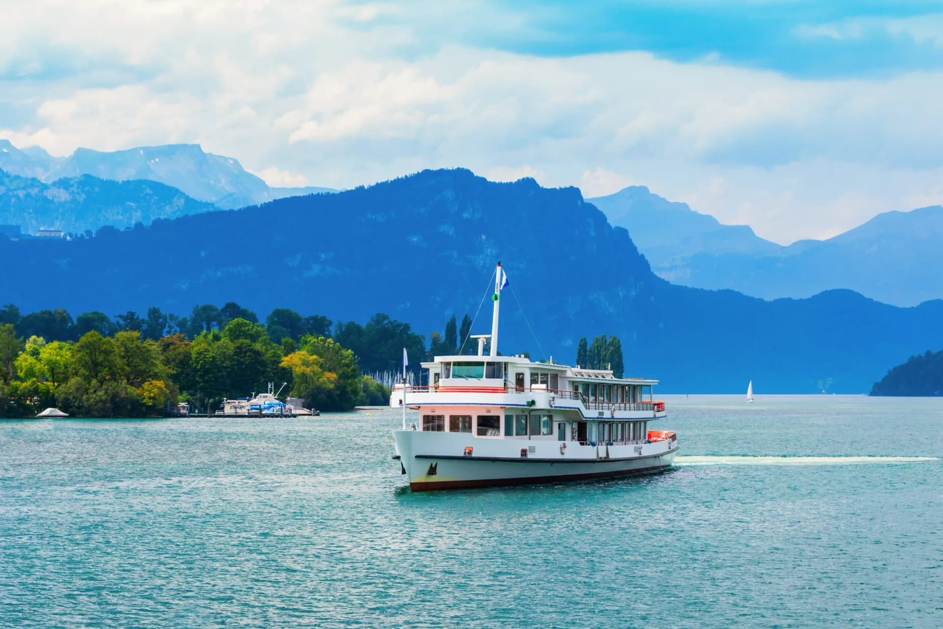 Tourist cruise boat on Lake Lucerne with blue mountains and cloudy sky background