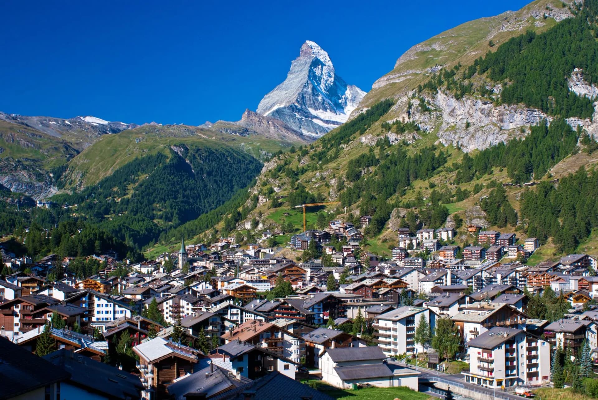 Matterhorn mountain above Zermatt village with traditional alpine architecture under clear blue sky