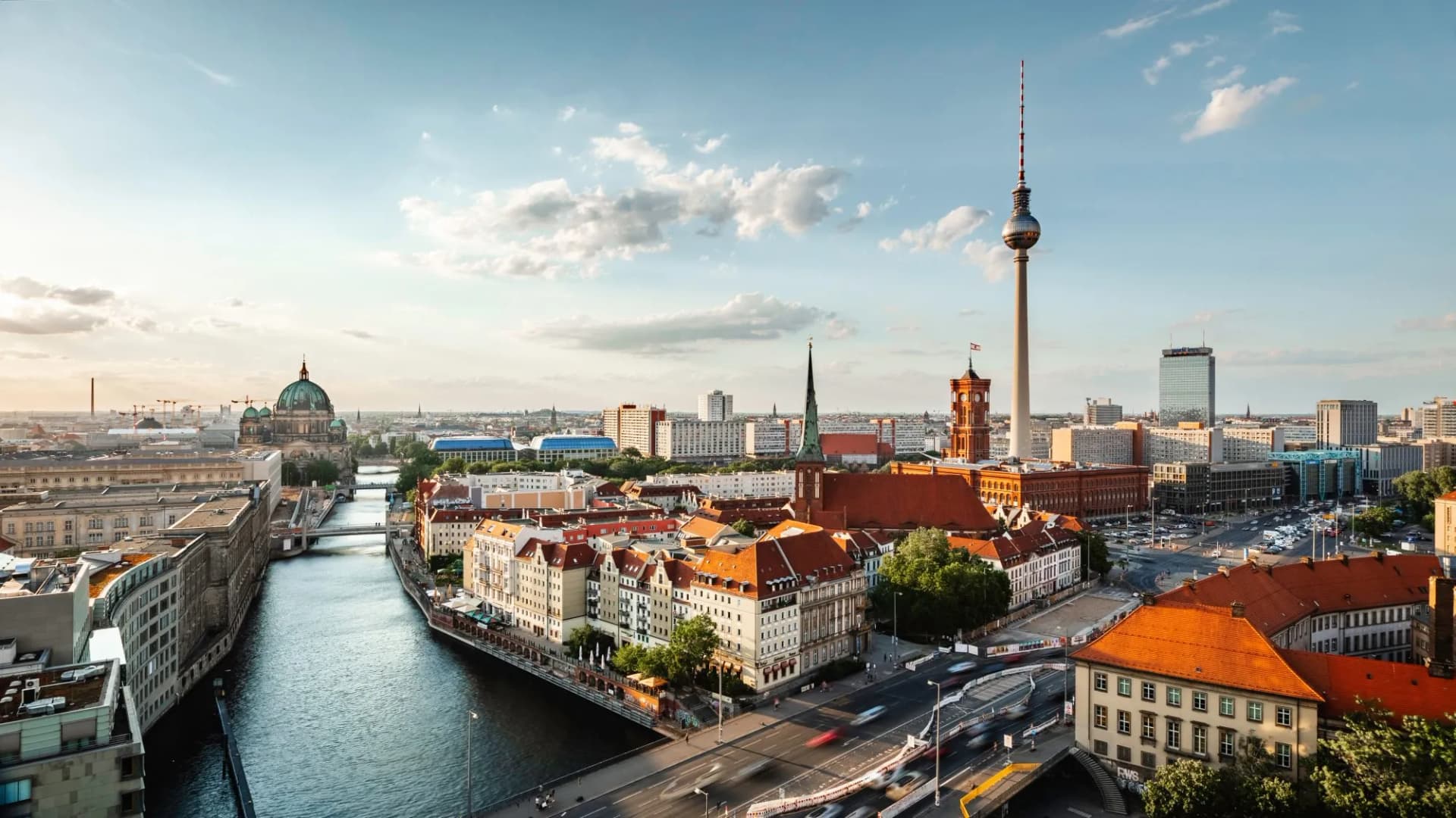 Berlin cityscape with Spree River, Berlin Cathedral, and TV Tower under a partly cloudy sky.