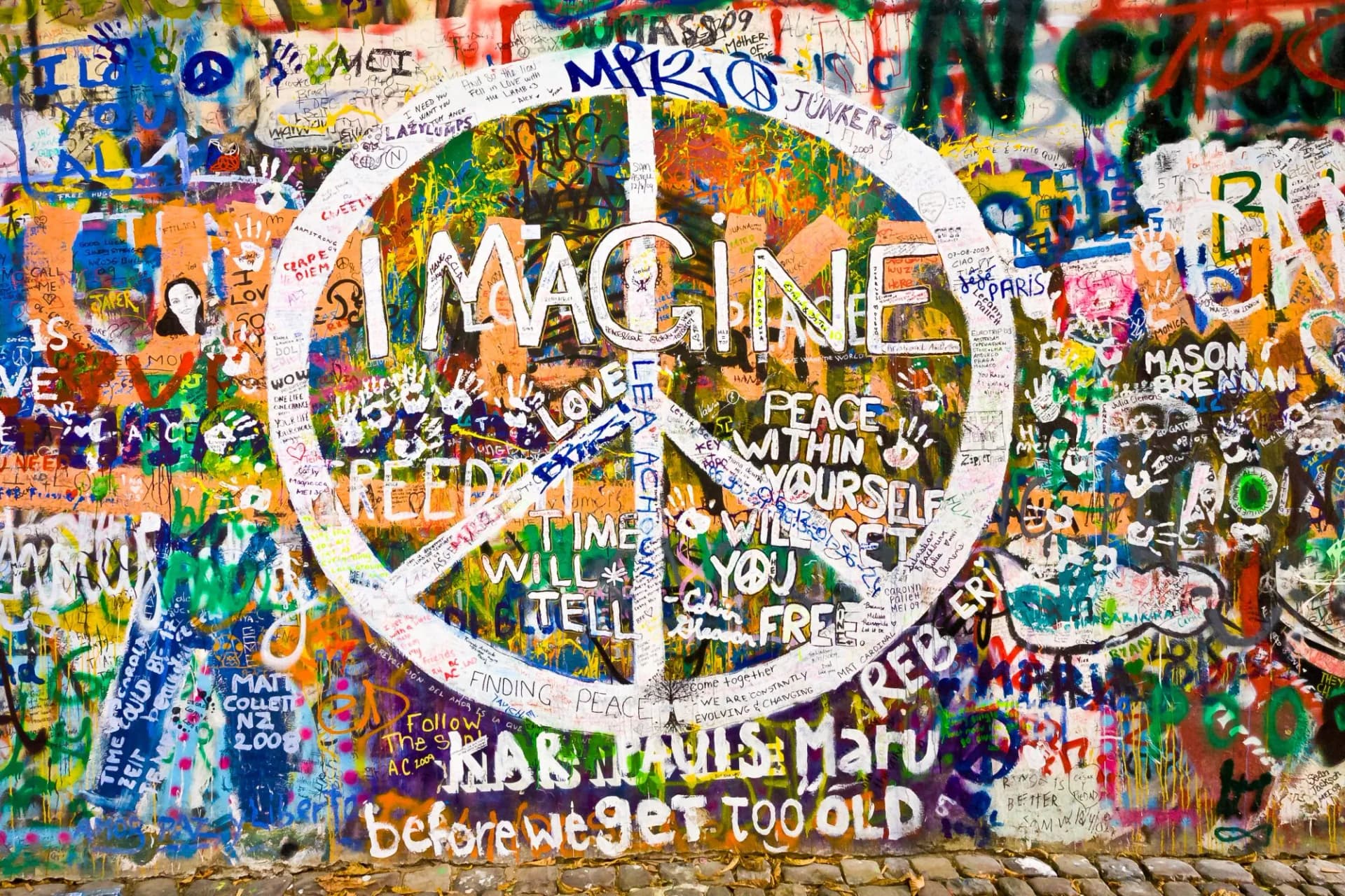 Colorful graffiti wall featuring a large white peace sign with the word "IMAGINE" written inside.
