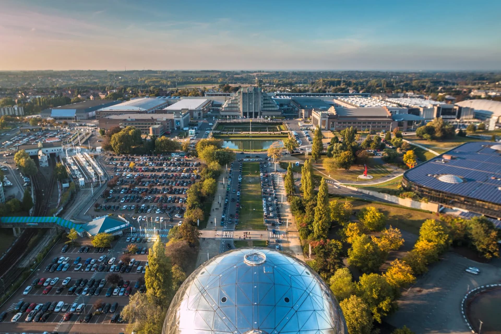View of Brussels from Atomium dome overlooking park, buildings, and parking lots.