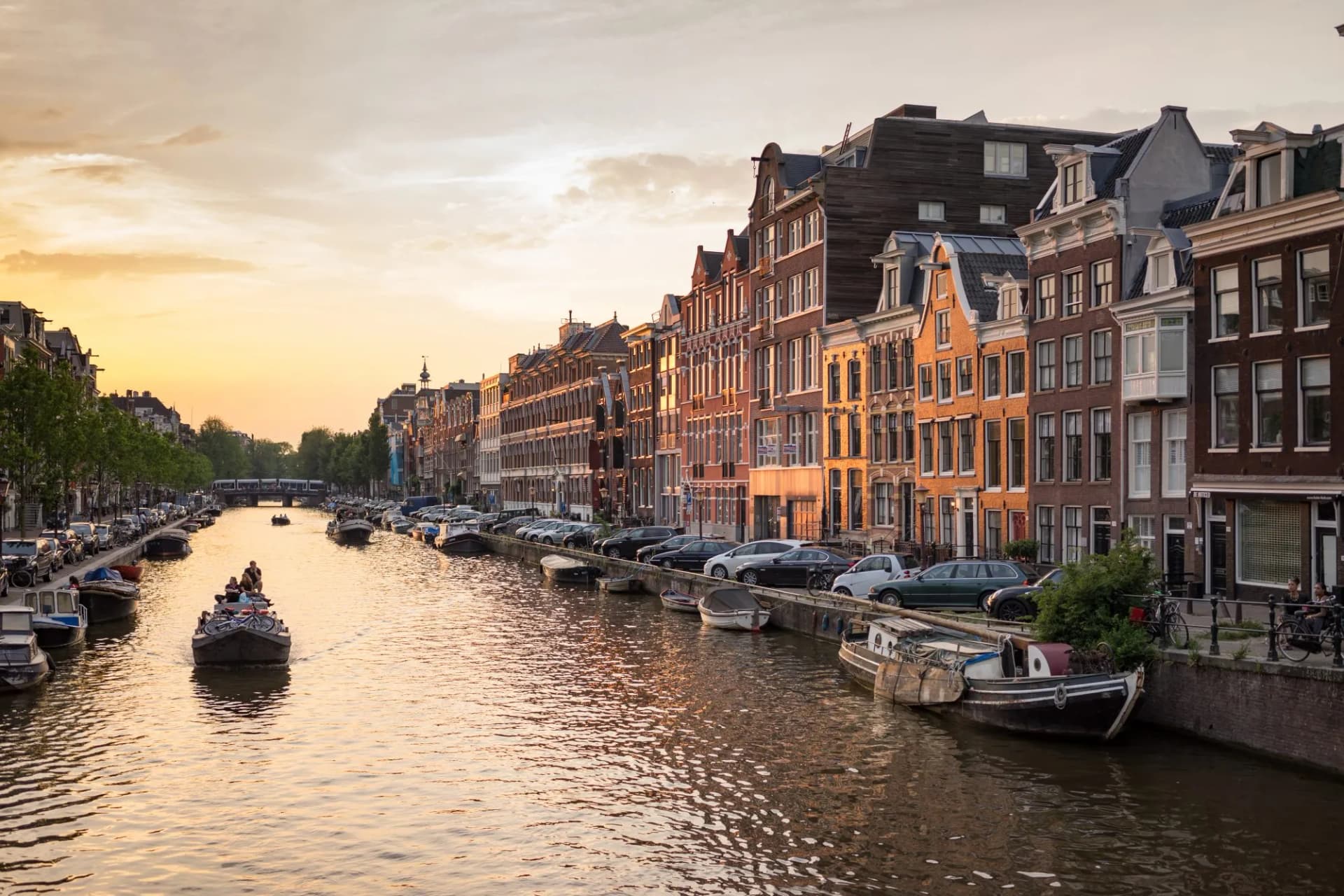 Boats on Prinsengracht canal with historic buildings at sunset in Amsterdam