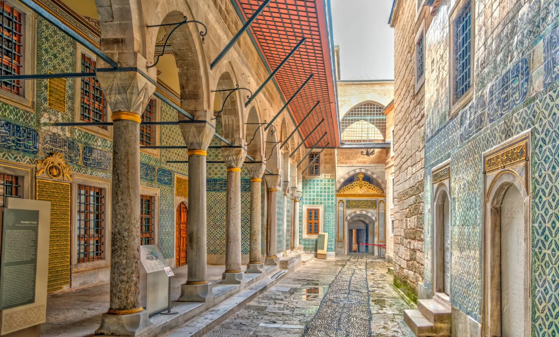 Covered walkway with ornate tilework and marble columns at Topkapi Palace in Istanbul.