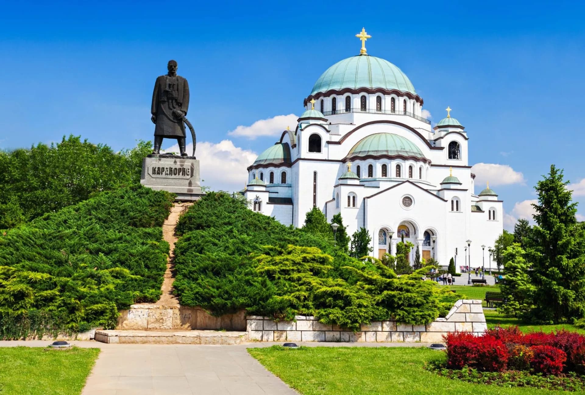 White Church of Saint Sava with green domes and Karadjordje statue in Belgrade park