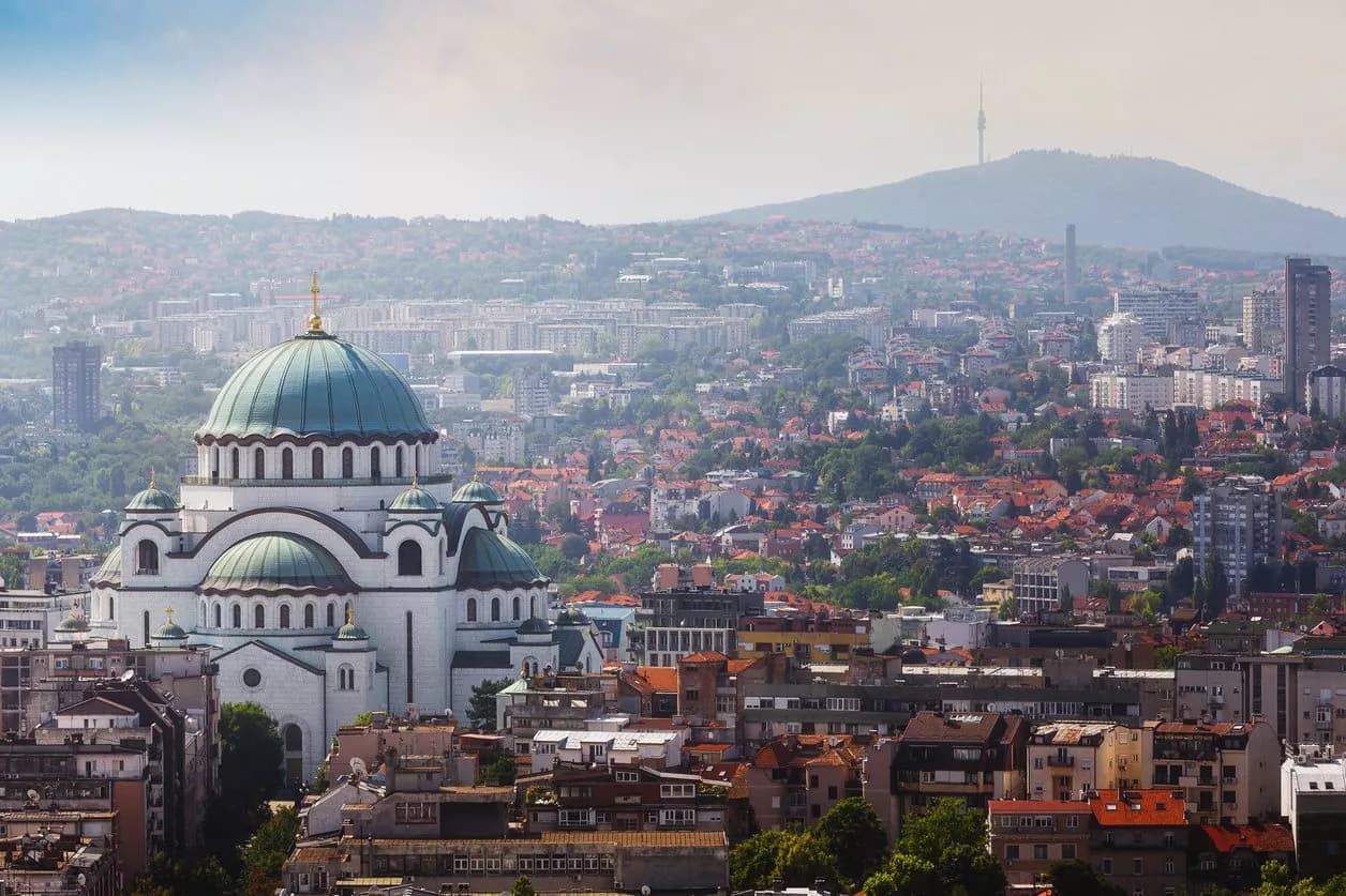 Saint Sava Temple dome overlooks the dense cityscape of Belgrade, Serbia, with a hill in the background.