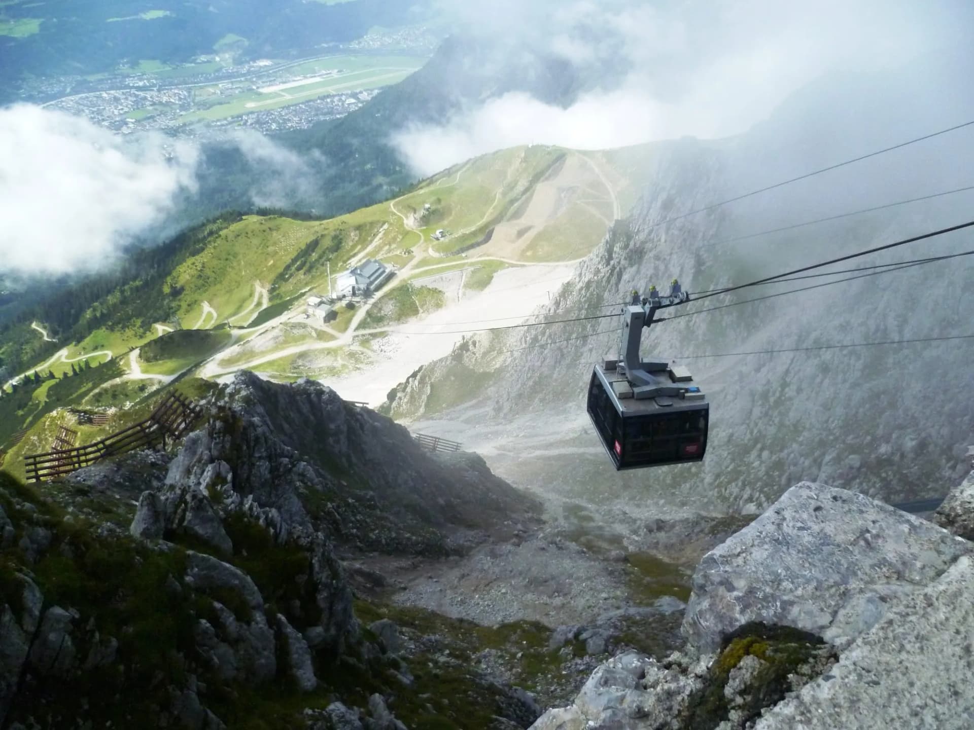 Cable car above Nordkette trail with Innsbruck valley visible below in the Austrian Alps.
