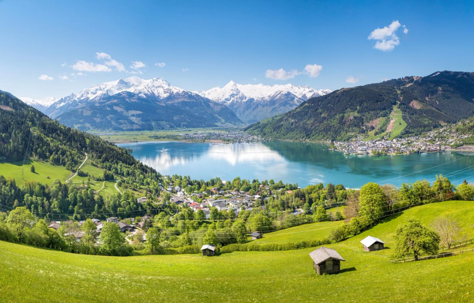 View over Zell am See in summer with snow-capped Alps reflecting in the lake.