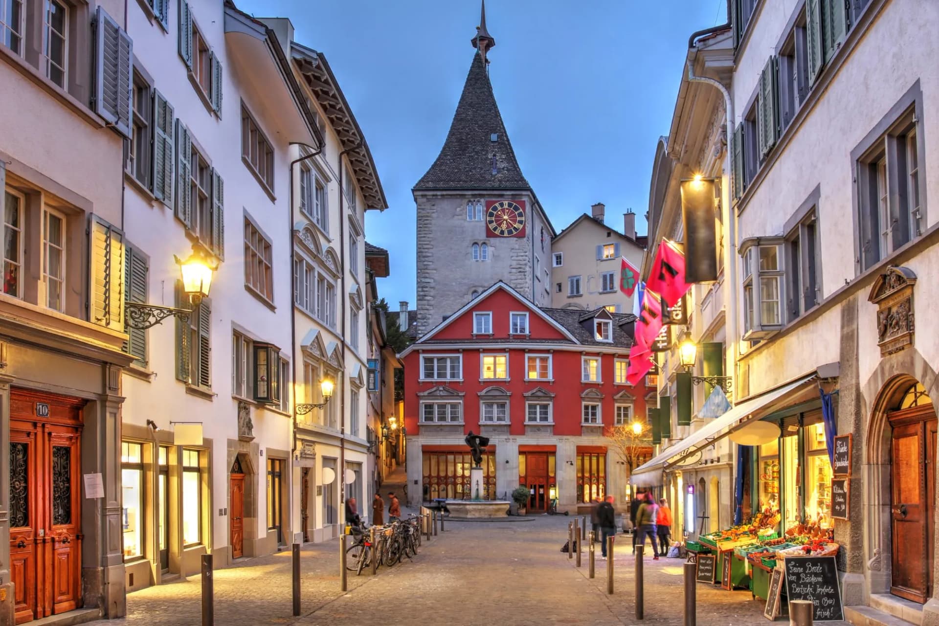 Street in old town Zurich, Switzerland, featuring the clock tower at dusk.