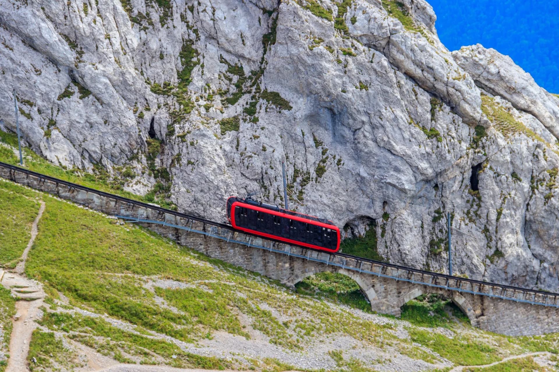 Red cogwheel train climbing Mount Pilatus in Canton Lucerne, Switzerland, on steep tracks.