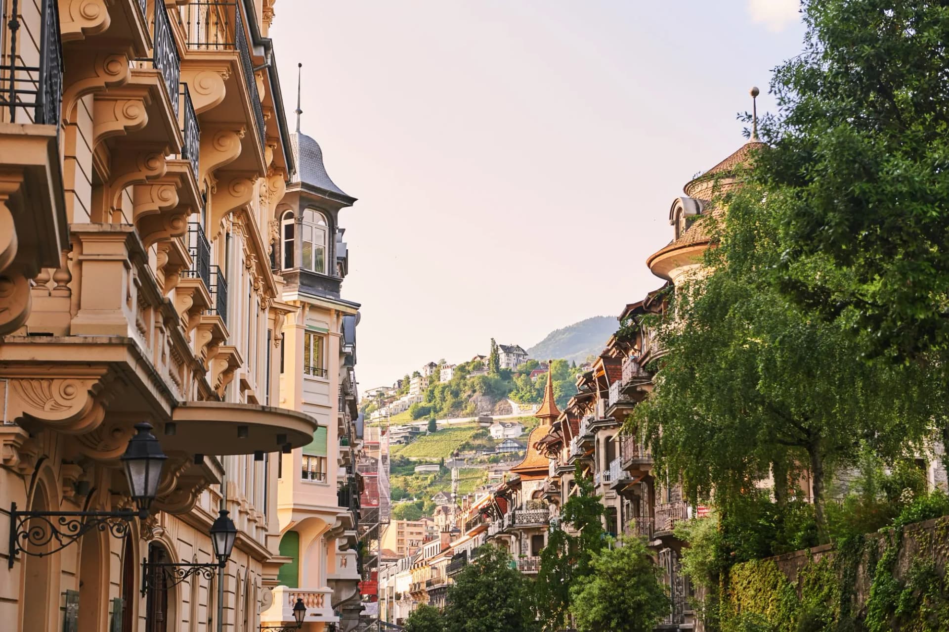 Small street in Montreux, Vaud, Switzerland, with ornate buildings and hillside homes.