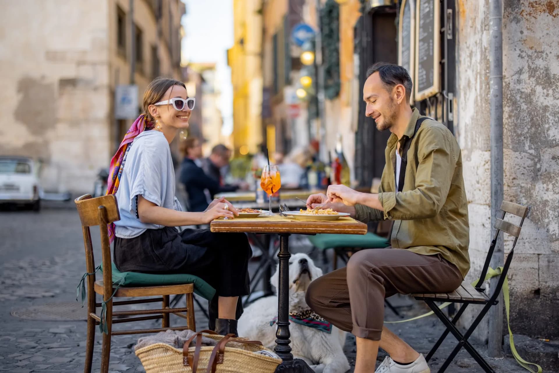 Couple eating pasta and drinking aperitif outdoors at a street restaurant in Rome.