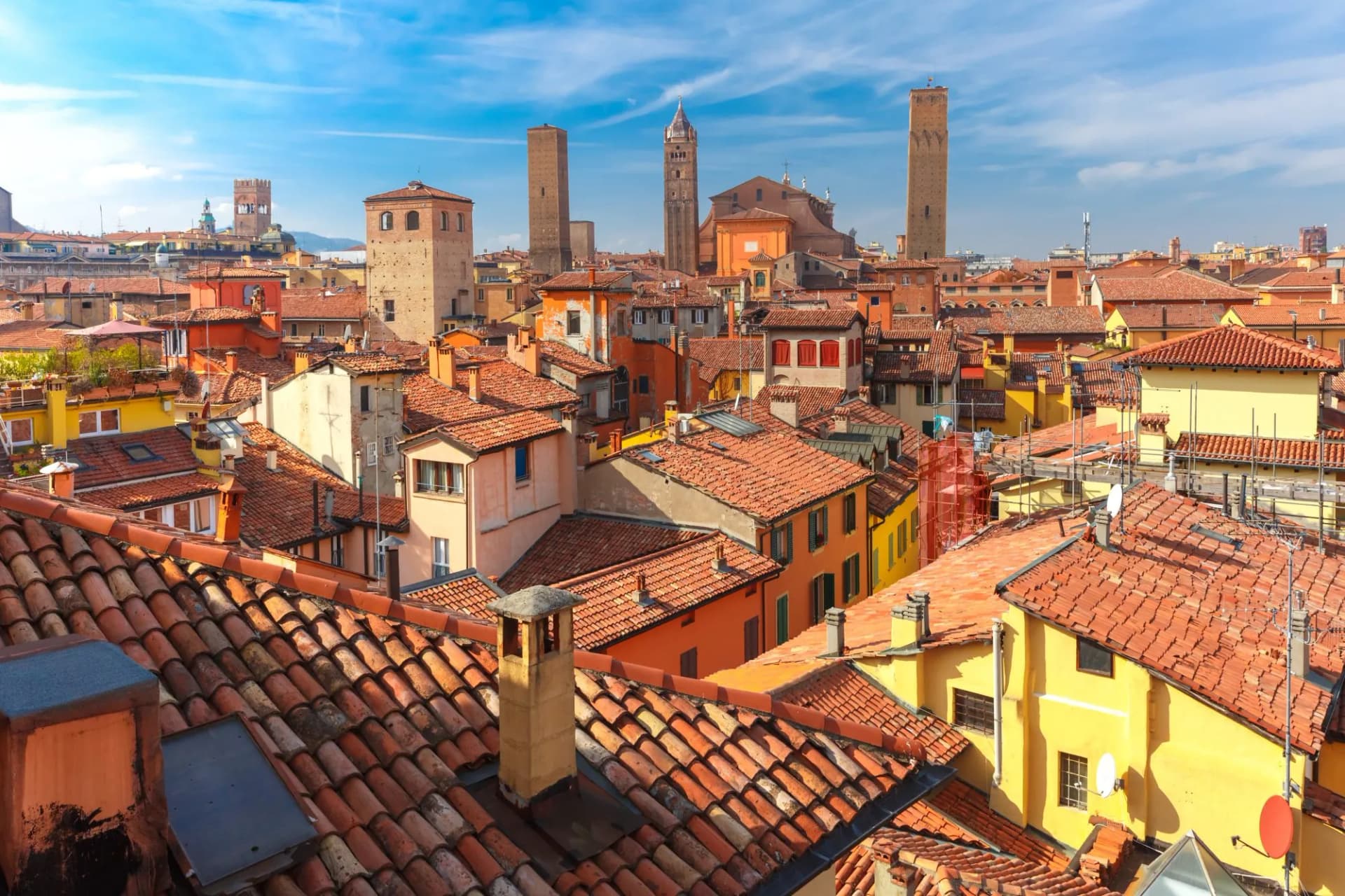 Aerial view of Bologna cathedral and towers towering above terracotta roofs of the old town on a sunny day in Italy.