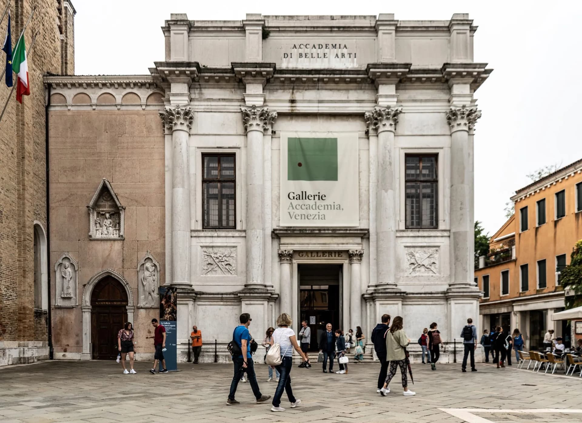 Facade of Gallerie dell'Accademia in Venice with tourists walking in the square.