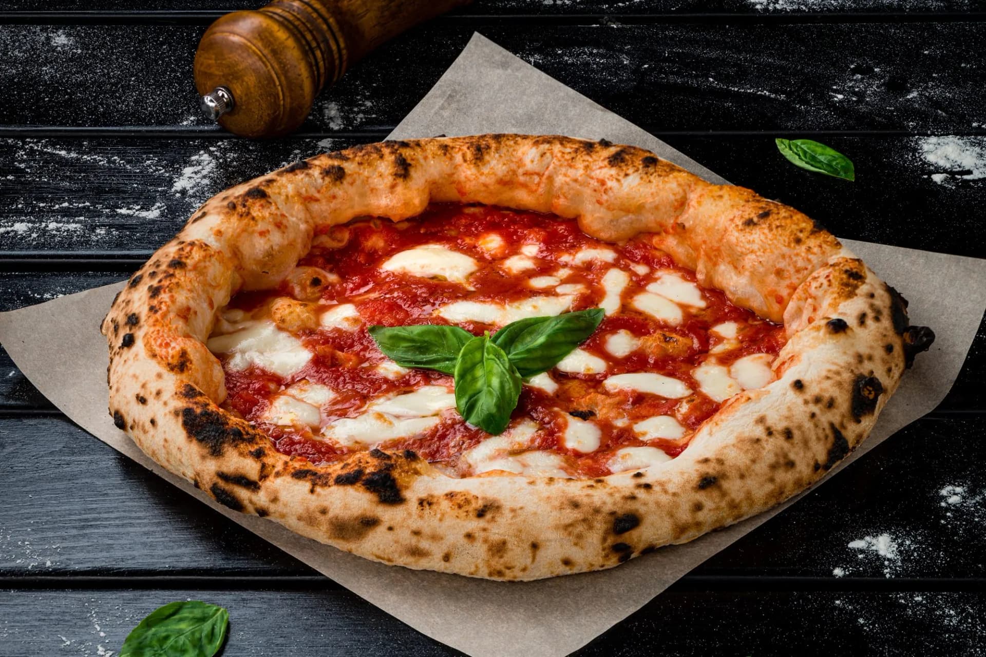 Traditional Pizza Margherita with fresh mozzarella and basil on parchment paper, dark background.