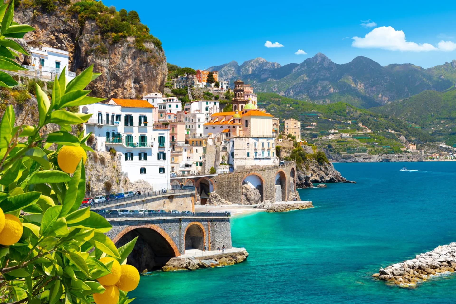 Lemons in foreground of Amalfi coastal view with white buildings and mountains, Italy.