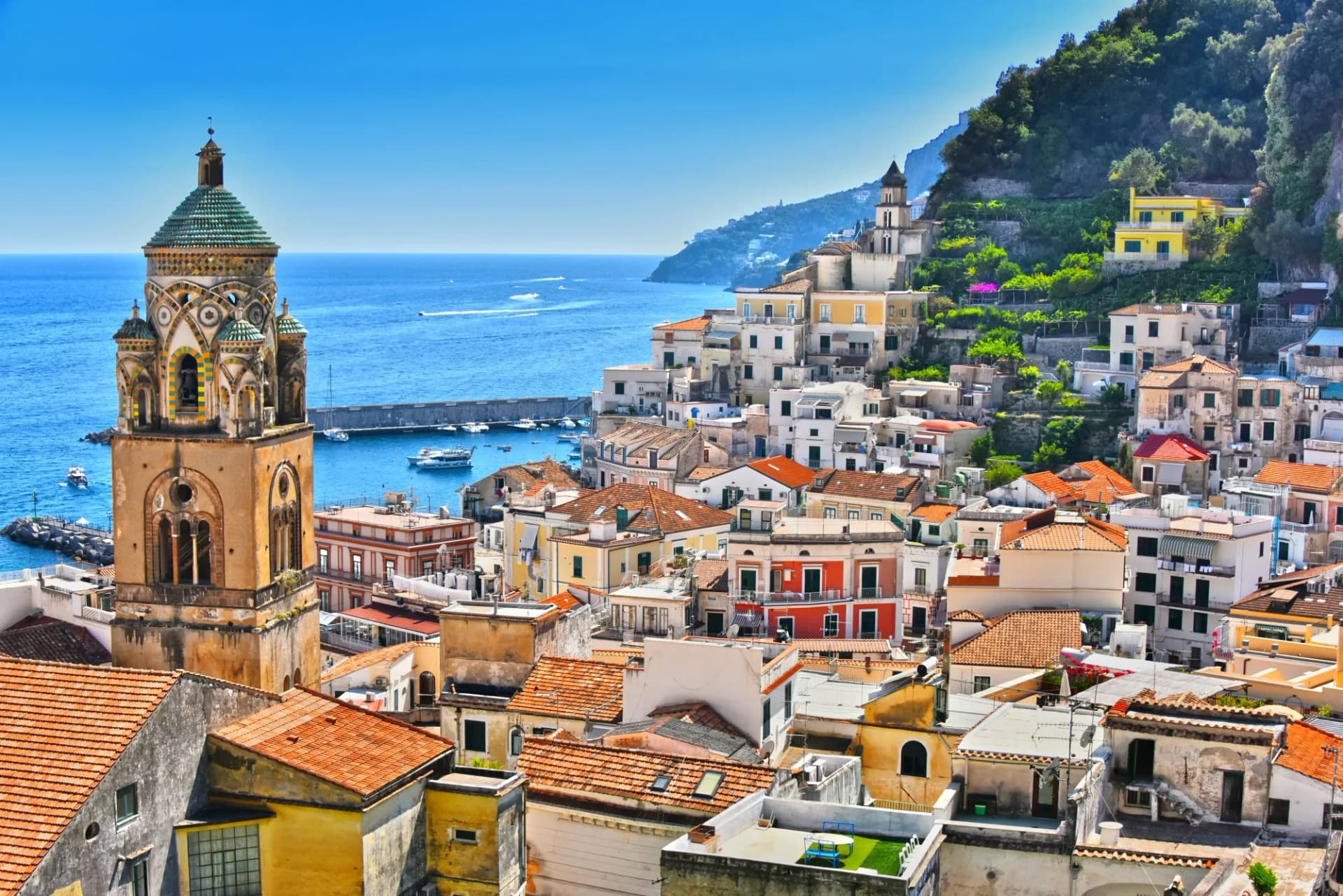 Amalfi town with colorful buildings, bell tower, and boats on the blue sea in Salerno, Campania, Italy.