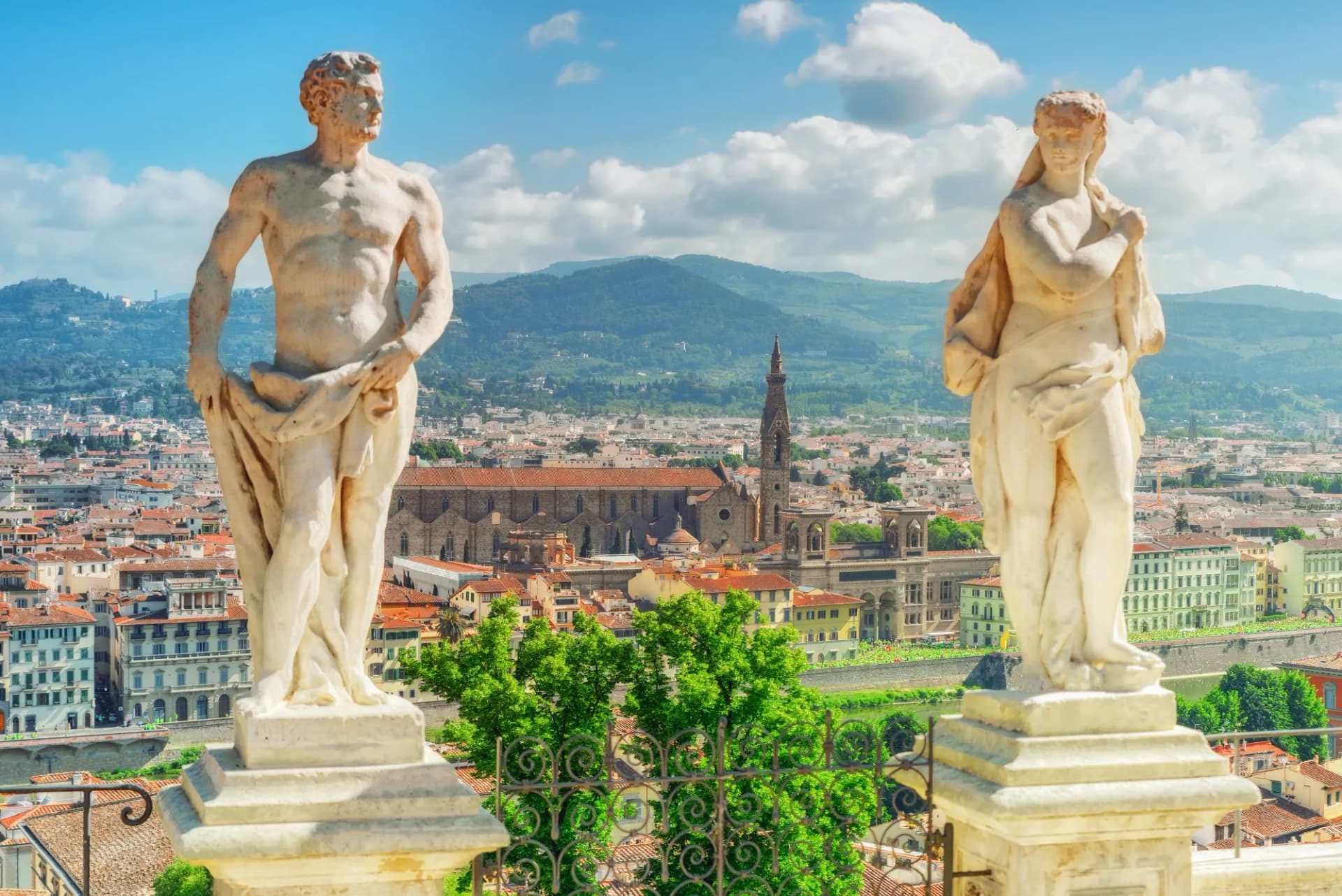 Statues overlooking Florence panorama from Boboli Gardens, with mountains in the background.