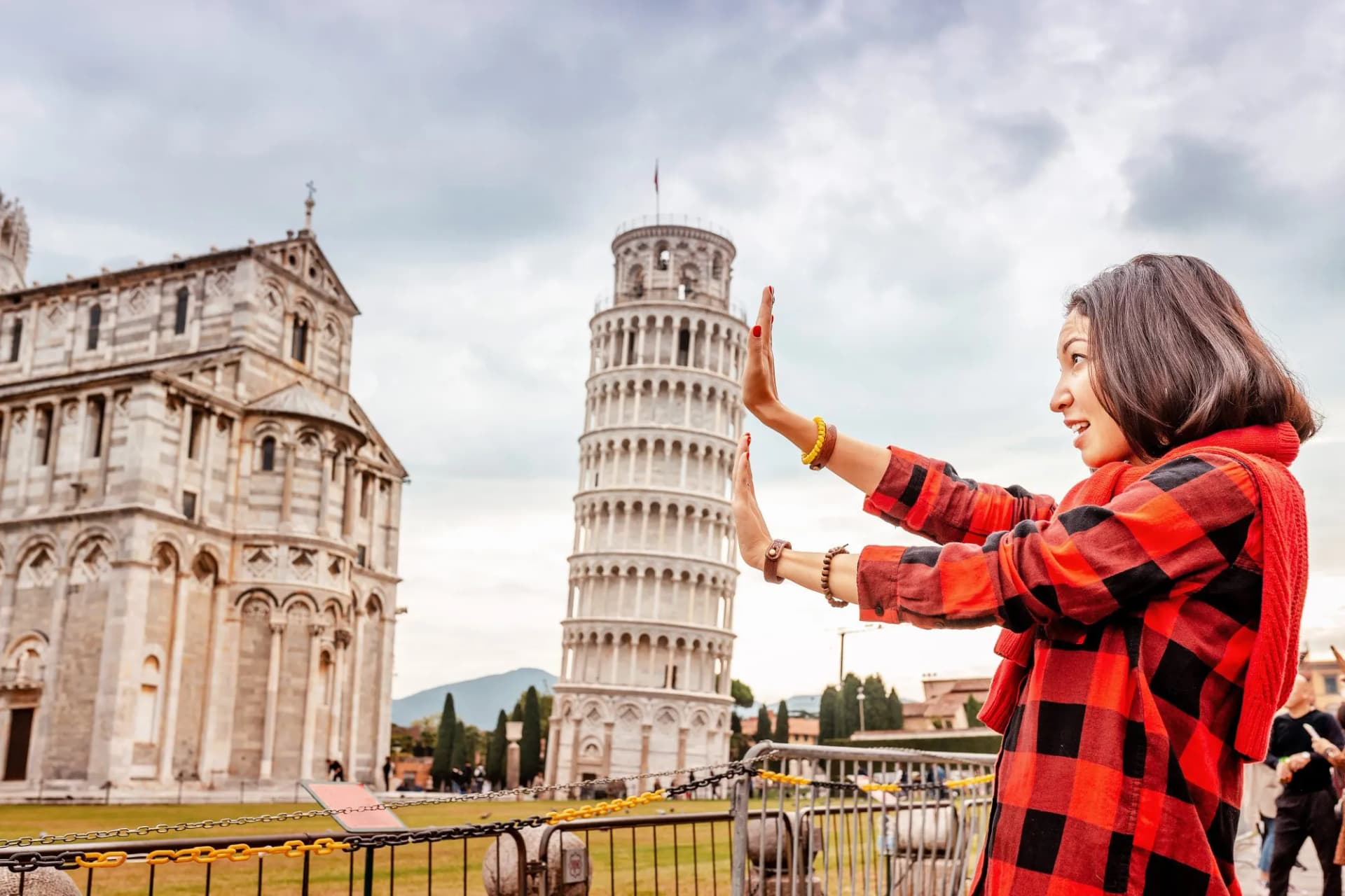 Tourist posing with the Leaning Tower of Pisa and the adjacent cathedral in Italy.