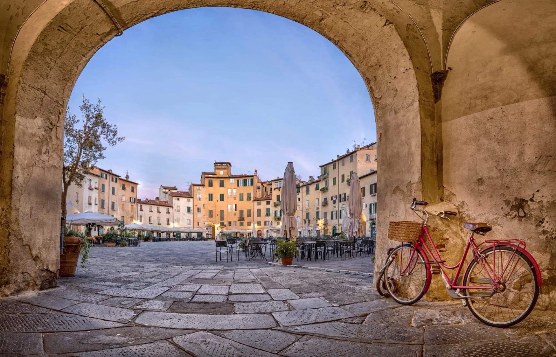 View of Piazza dell'Anfiteatro square in Lucca, Italy through an archway with a bicycle.
