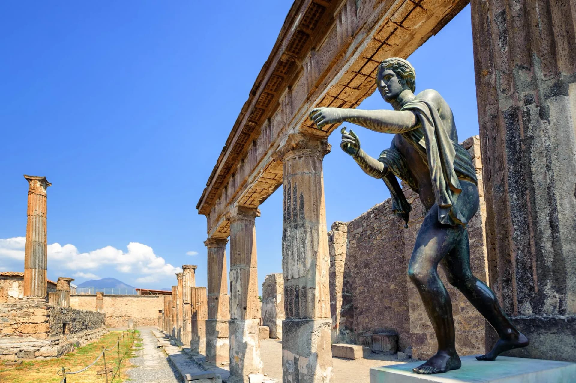 Bronze statue near Roman columns at the ruins of Apollo Temple in Pompeii, Naples, Italy.