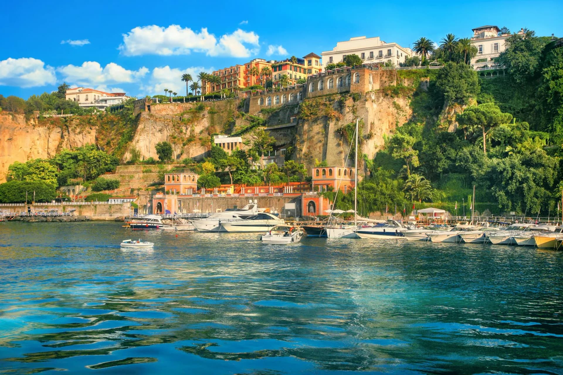 Boats docked in harbour below cliffside buildings in Sorrento, Campania, Italy.