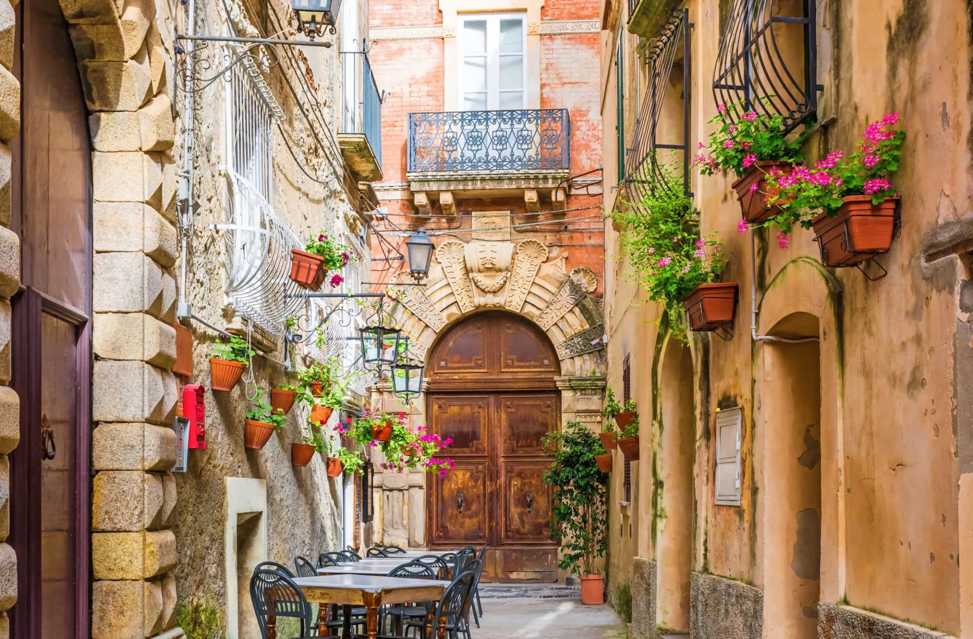 Cafe tables and chairs outside on a narrow street in Positano, Italy, with flower boxes.