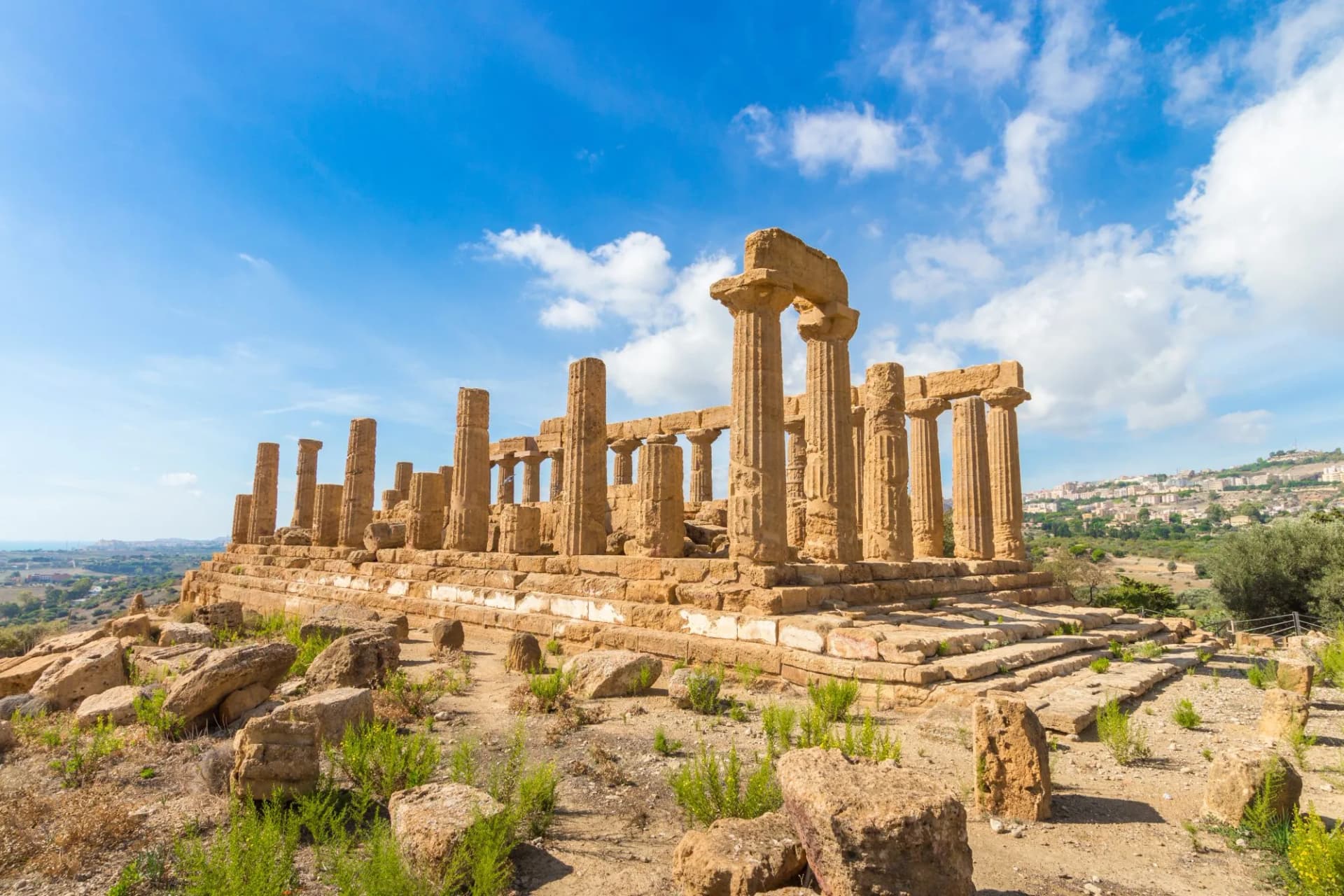 Ancient Greek temple ruins at the Valley of the Temples, Agrigento, under a blue sky.