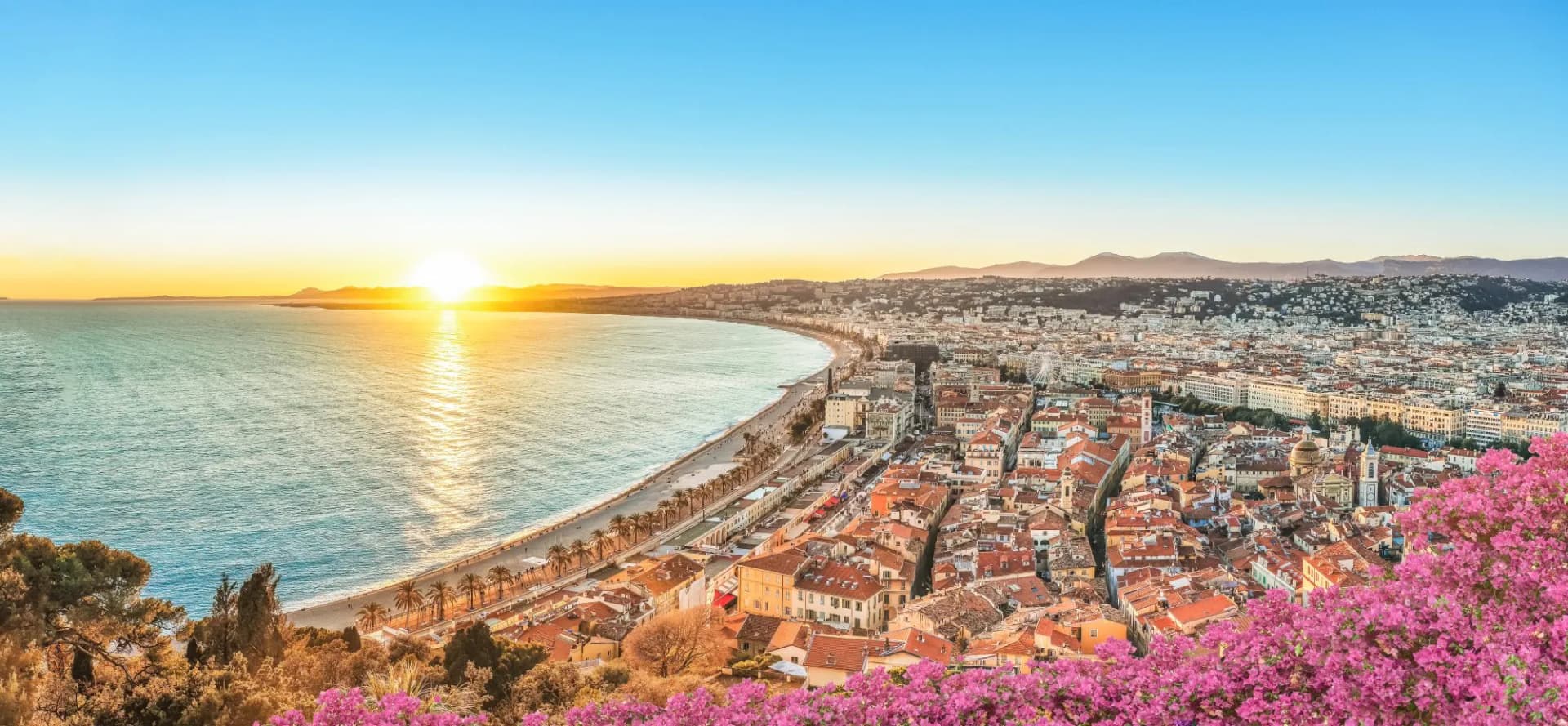 Cityscape of Nice, Cote d'Azur at sunset over the Mediterranean Sea with pink blossoms.