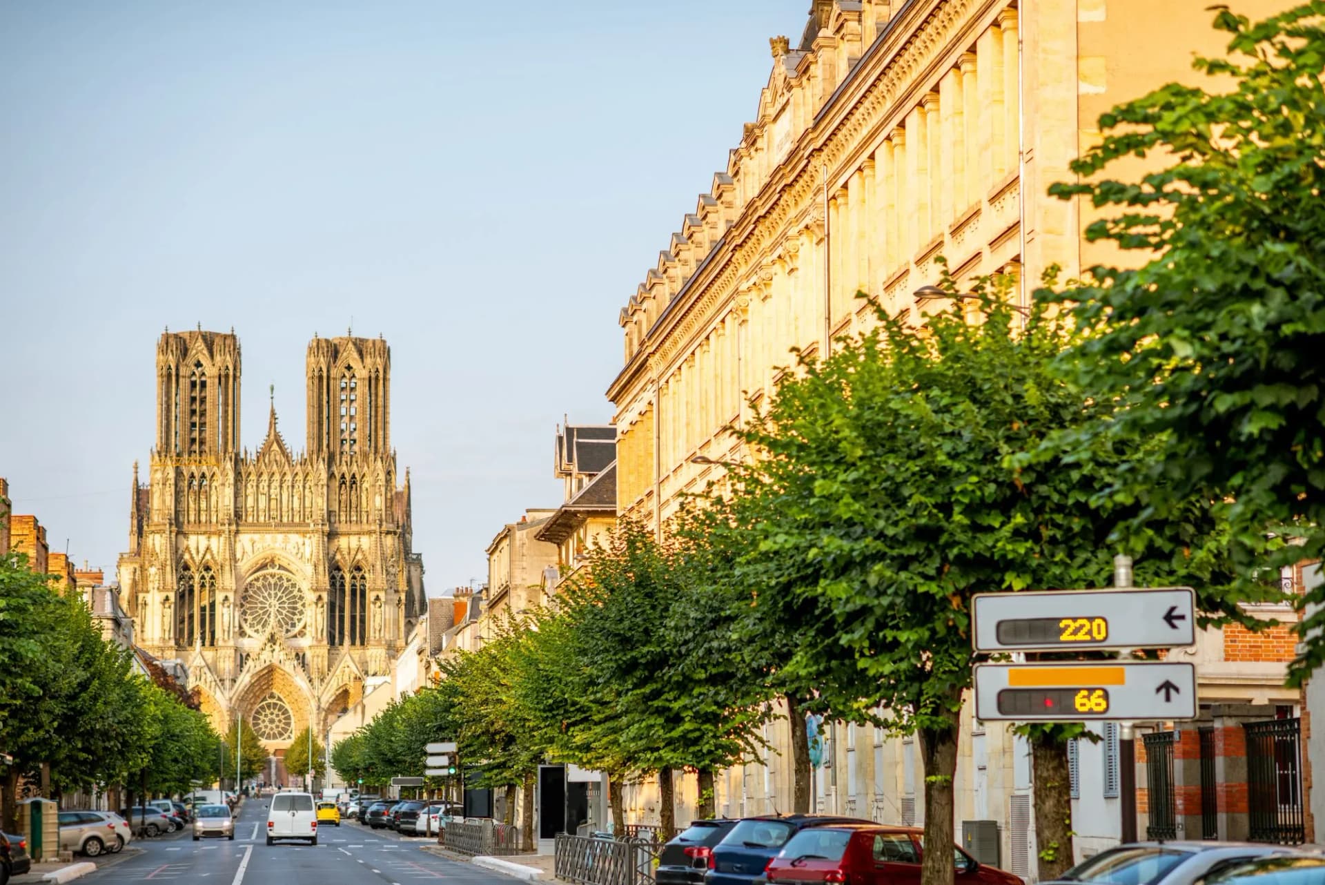 Street view toward Reims Cathedral with traffic signs and parked cars in Reims, France.