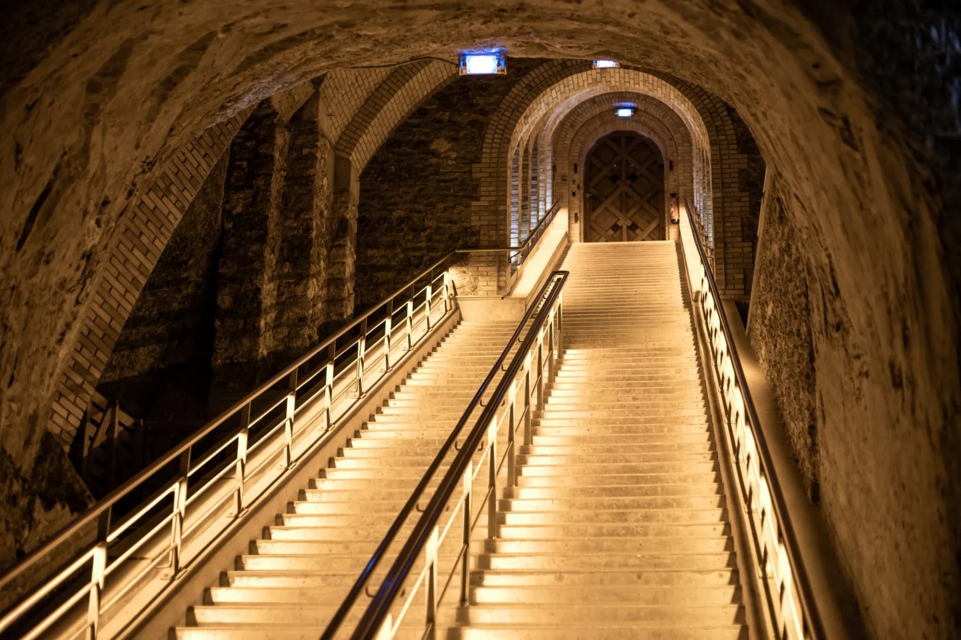 Illuminated stone staircase ascending in a deep underground cellar or cave in Reims, Champagne, France.