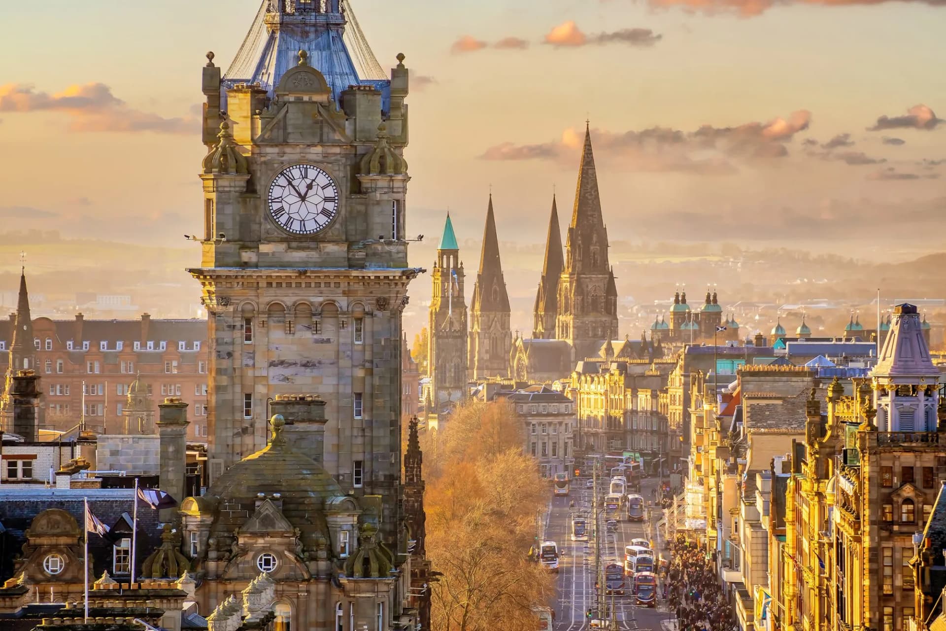 Old Town Edinburgh city skyline with prominent clock tower at sunset in Scotland.