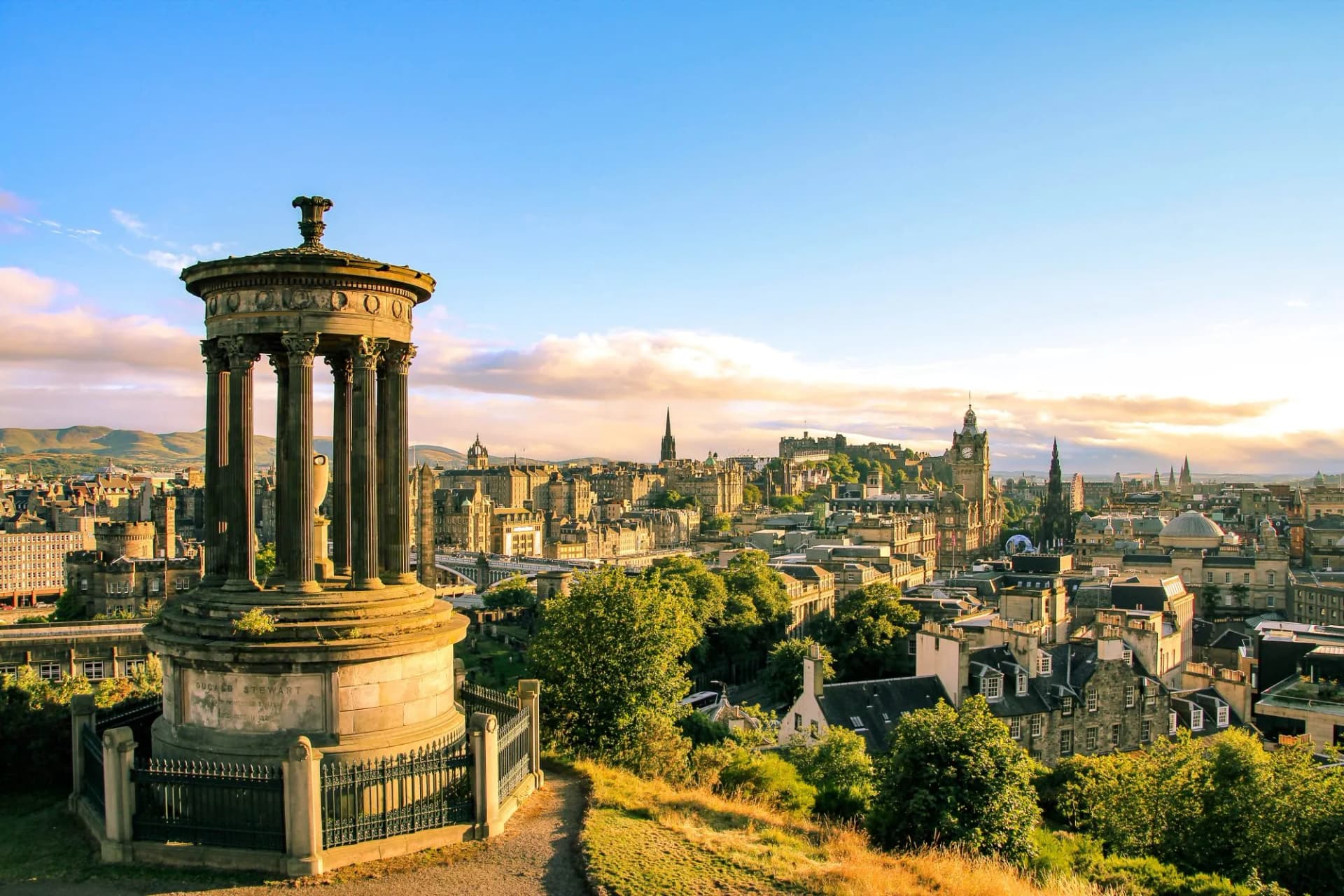 Dugald Stewart Monument overlooking Edinburgh skyline and hills at sunset from Calton Hill.