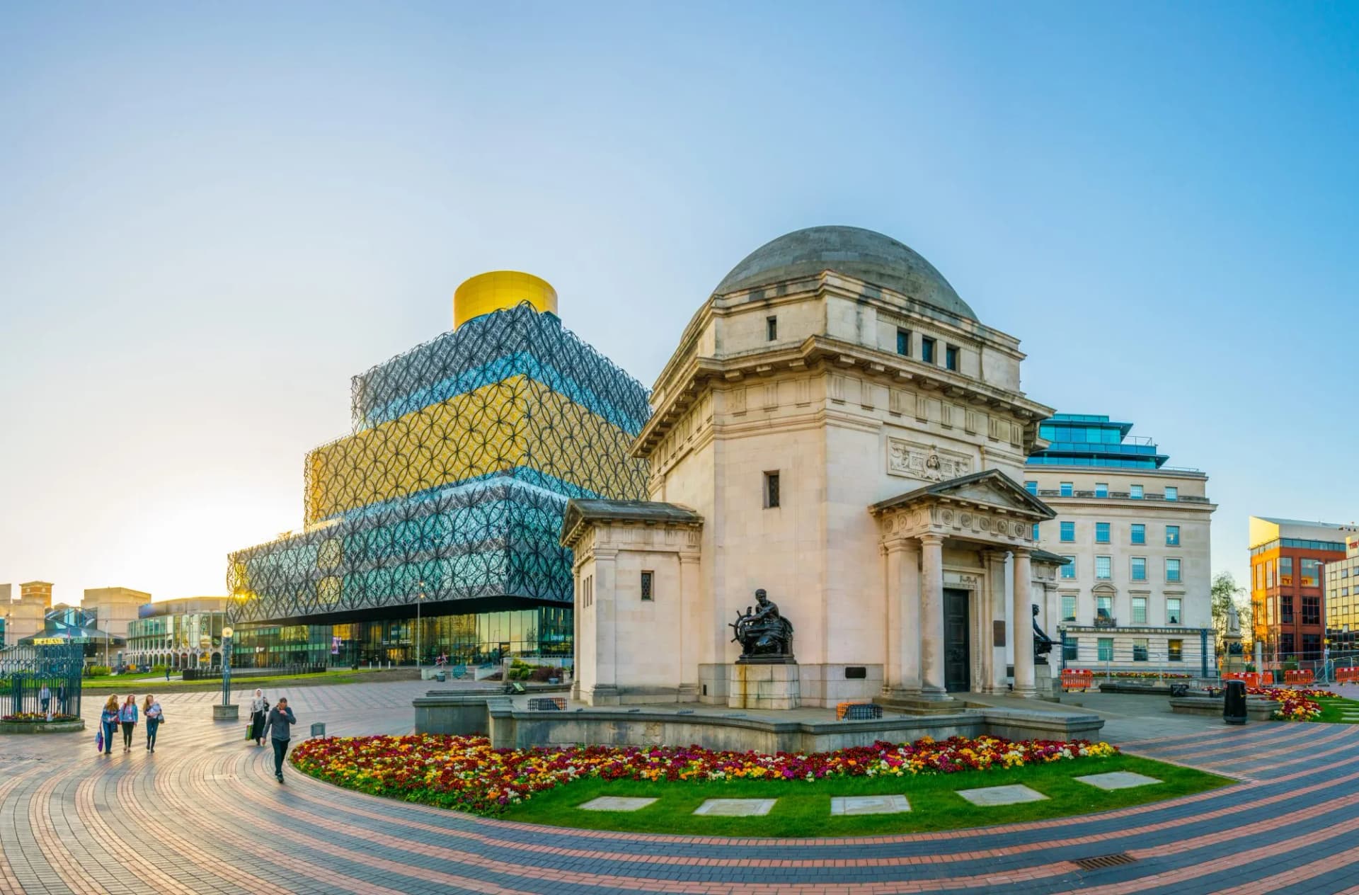 Library of Birmingham next to domed historic building with flower beds in paved square.