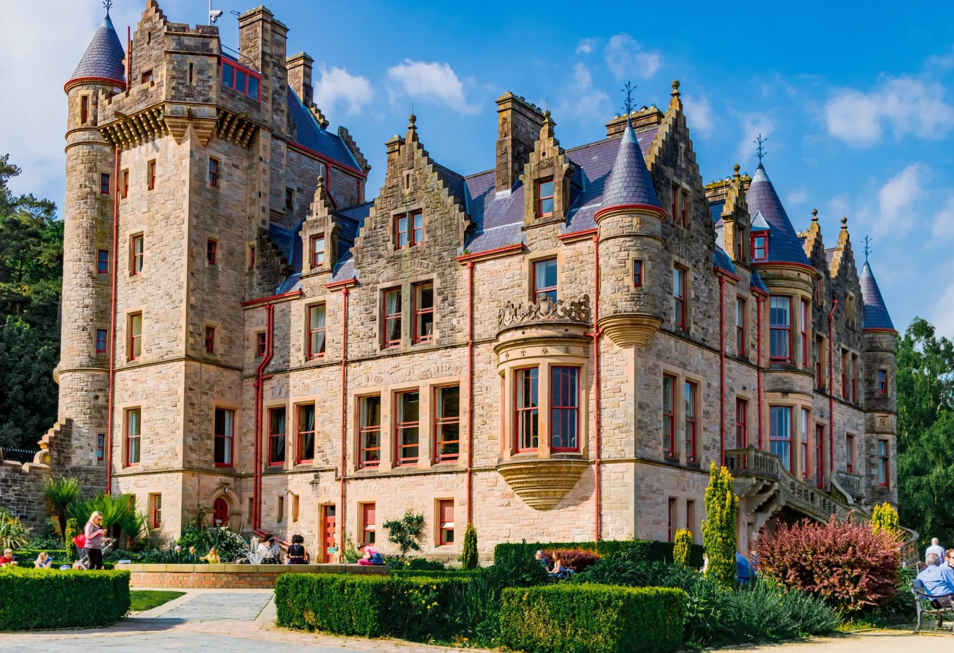 Belfast Castle stone facade with turrets and gardens under blue sky