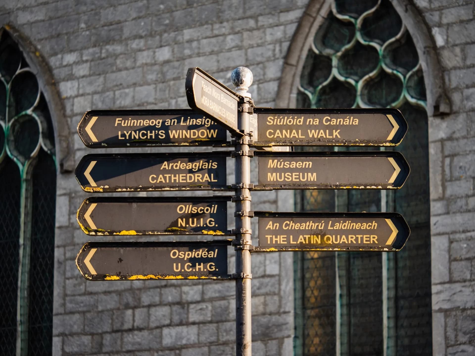 Galway city directional signpost pointing to Lynch's Window, Cathedral, Museum, Latin Quarter, and UCHG.