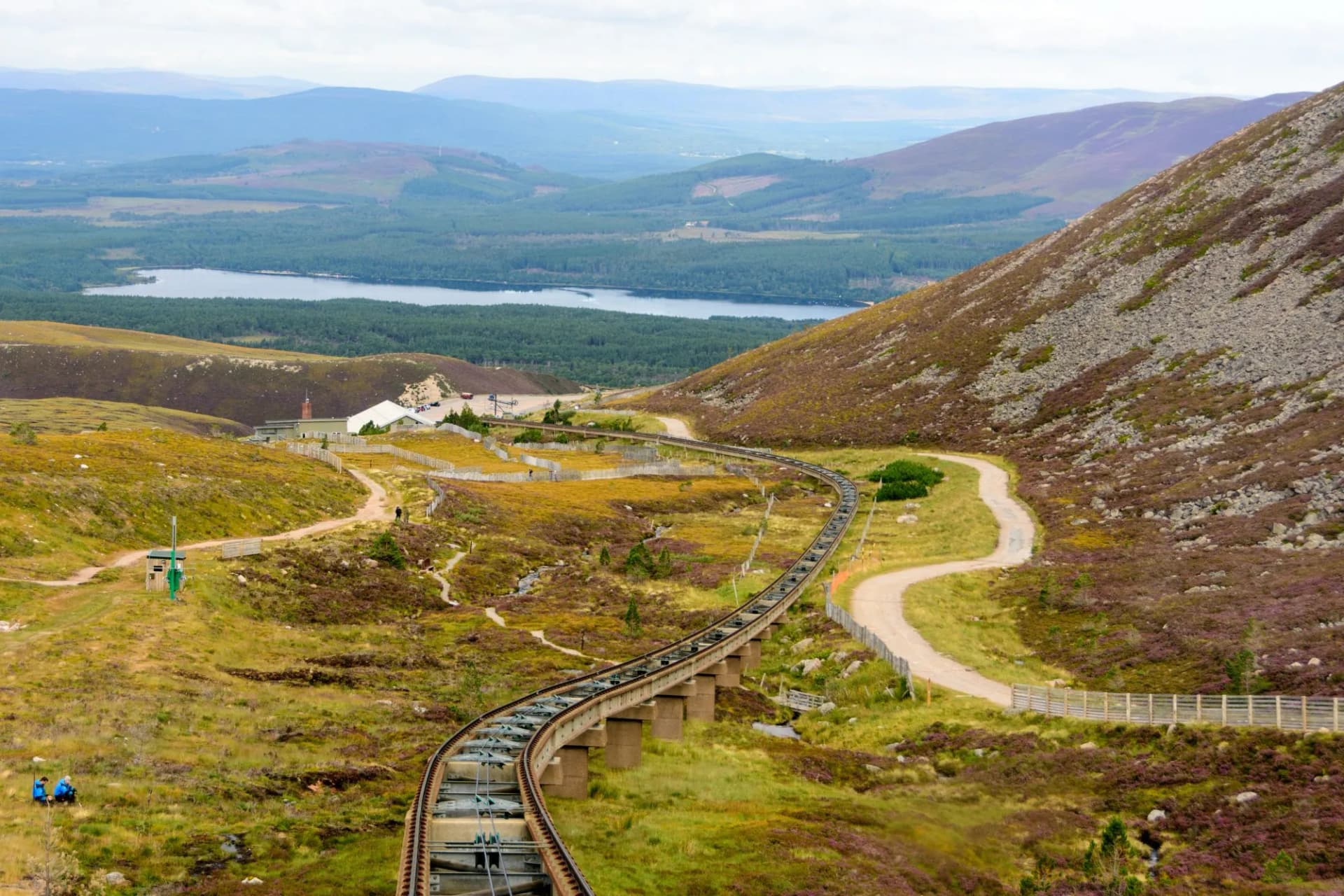 Funicular train tracks descending a hillside in Cairngorm National Park with a loch below.