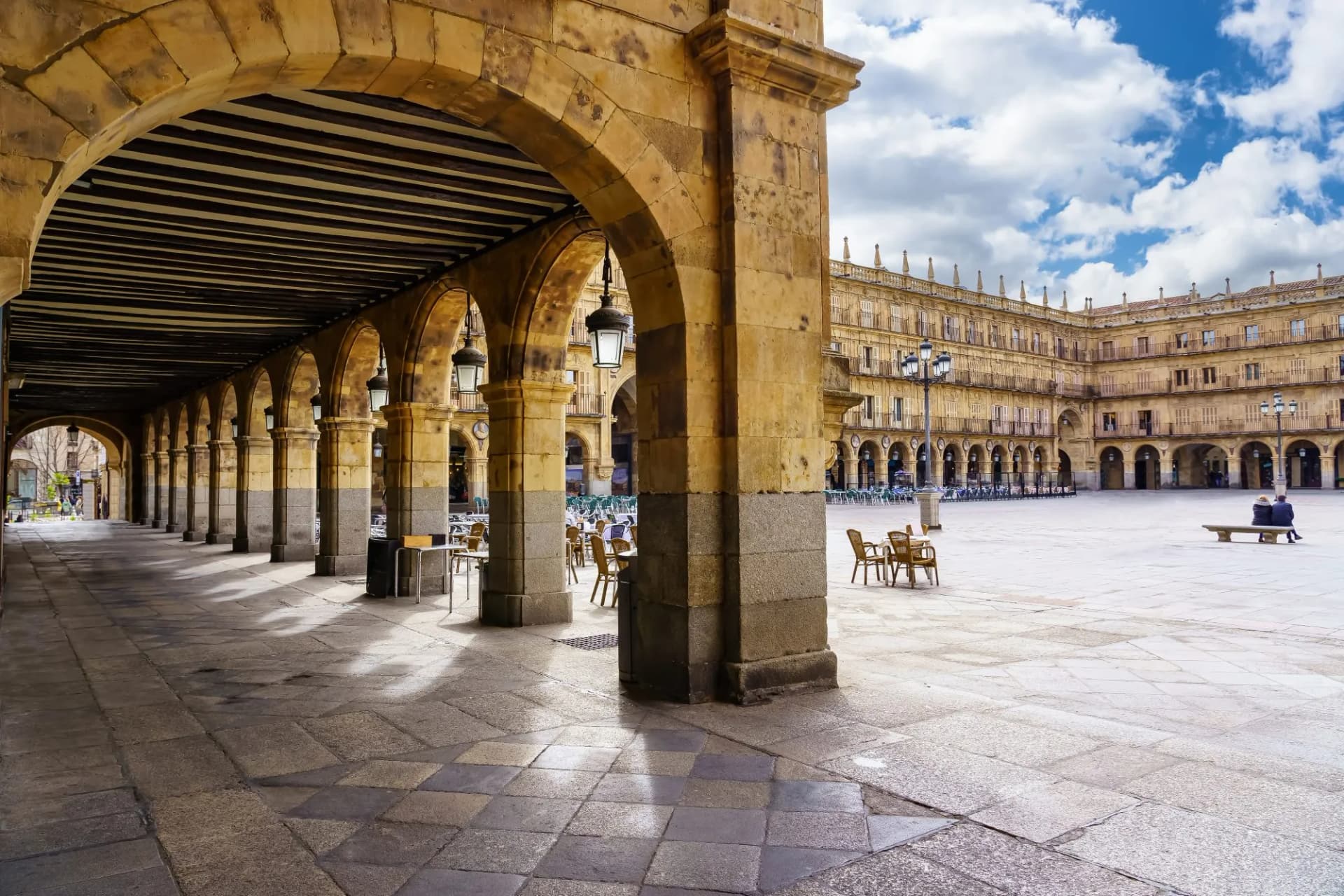 Plaza Mayor of Salamanca on a sunny day, showing stone arches and surrounding architecture.