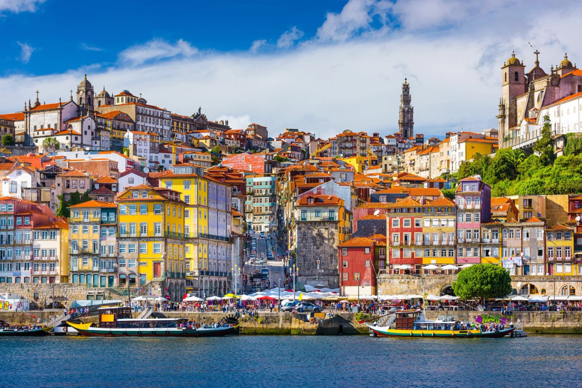 Porto Portugal old city skyline on the Douro River with colorful buildings and tour boats.