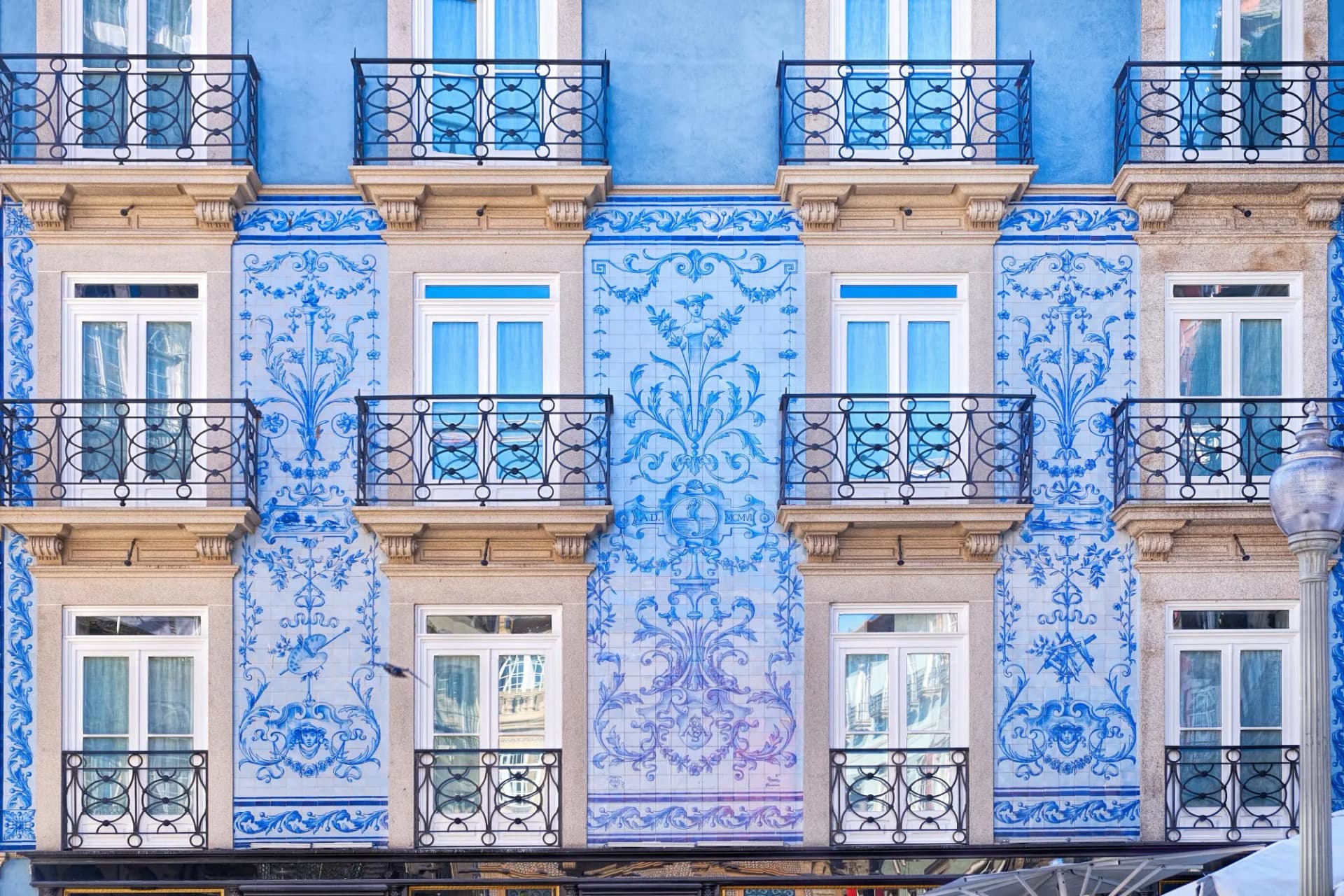 Traditional historic facade in Porto decorated with blue and white azulejo tiles and iron balconies.