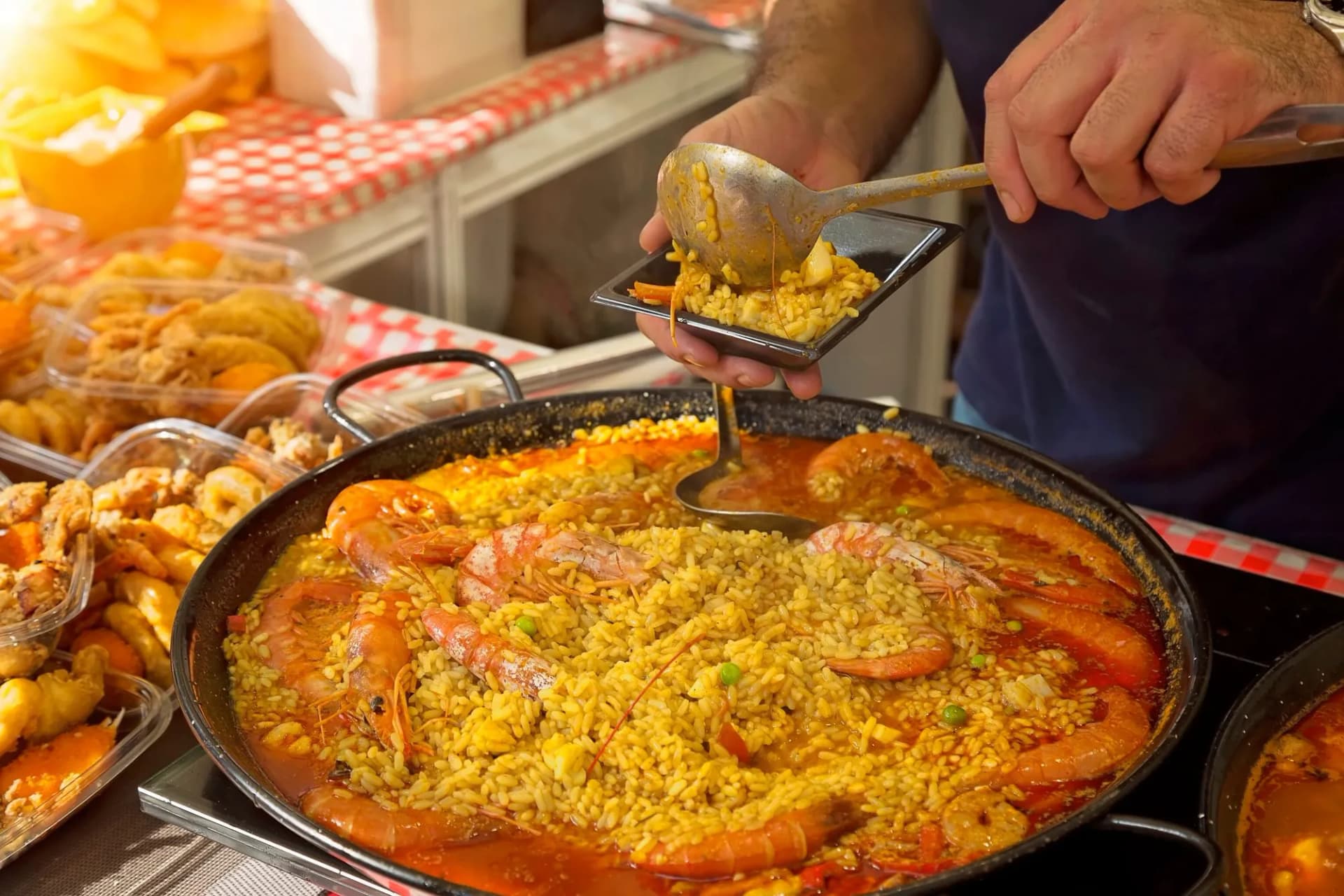 Serving seafood paella from a large pan at a street market stand near Barcelona Cathedral Square.