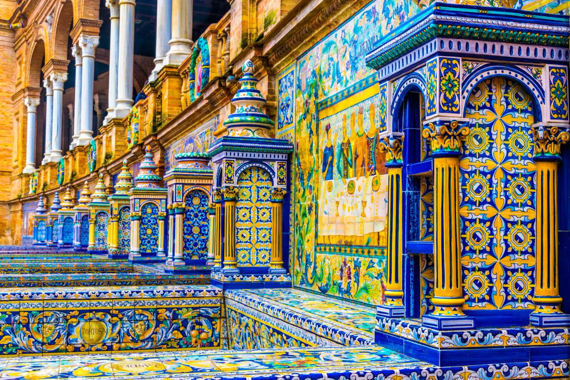Ornate blue and yellow tiled walls and columns at Plaza de España, Seville, Spain.