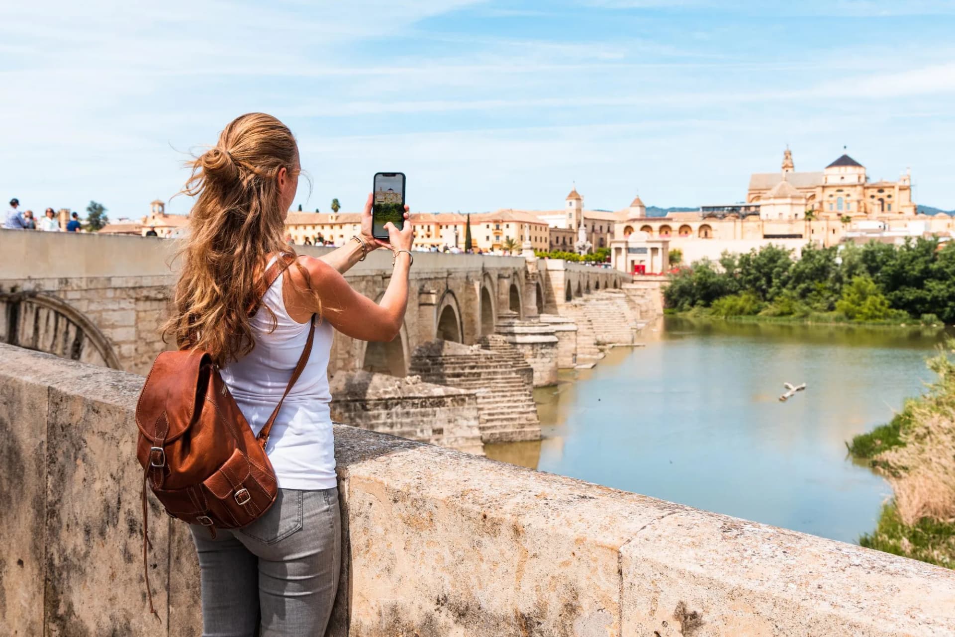 Woman taking photo of Roman Bridge and Mezquita-Cathedral in Cordoba, Andalusia