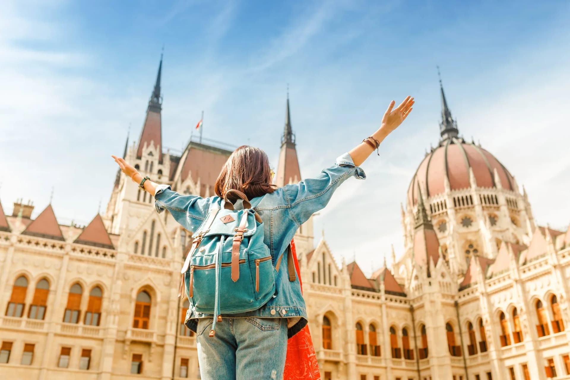 Woman tourist with backpack enjoying view of the Parliament Building in Budapest, Hungary.