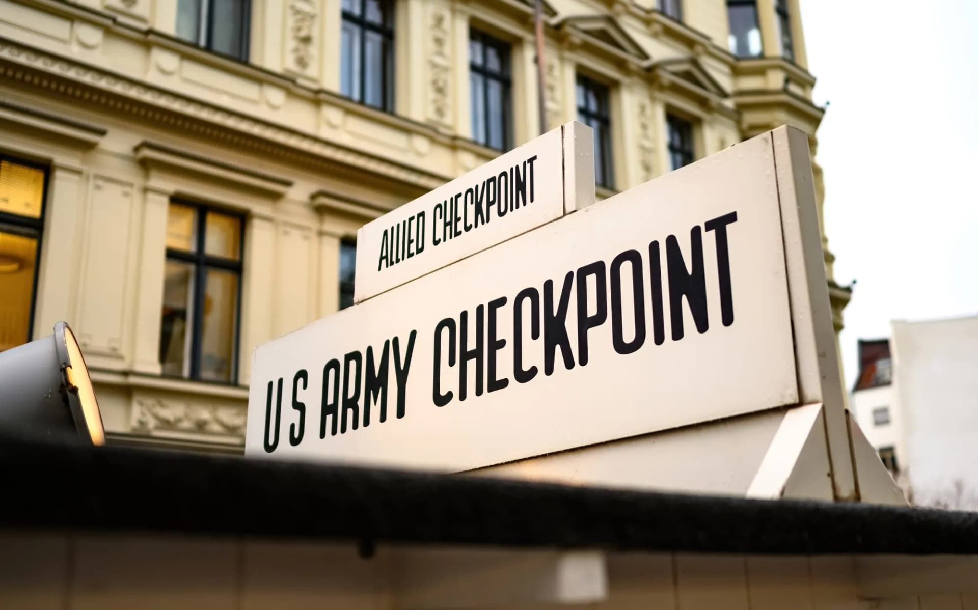US Army Checkpoint and Allied Checkpoint sign near a building, symbol of Cold War Berlin.