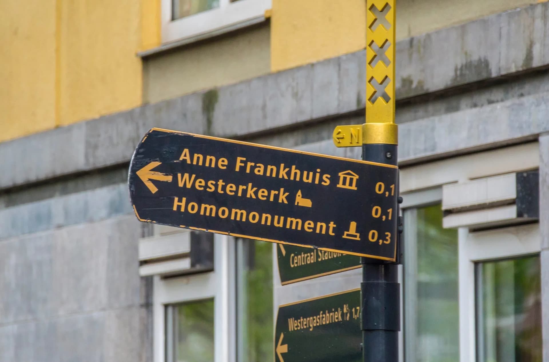 Direction sign pointing to Anne Frank House, Westerkerk, and Homomonument in Amsterdam, Netherlands.