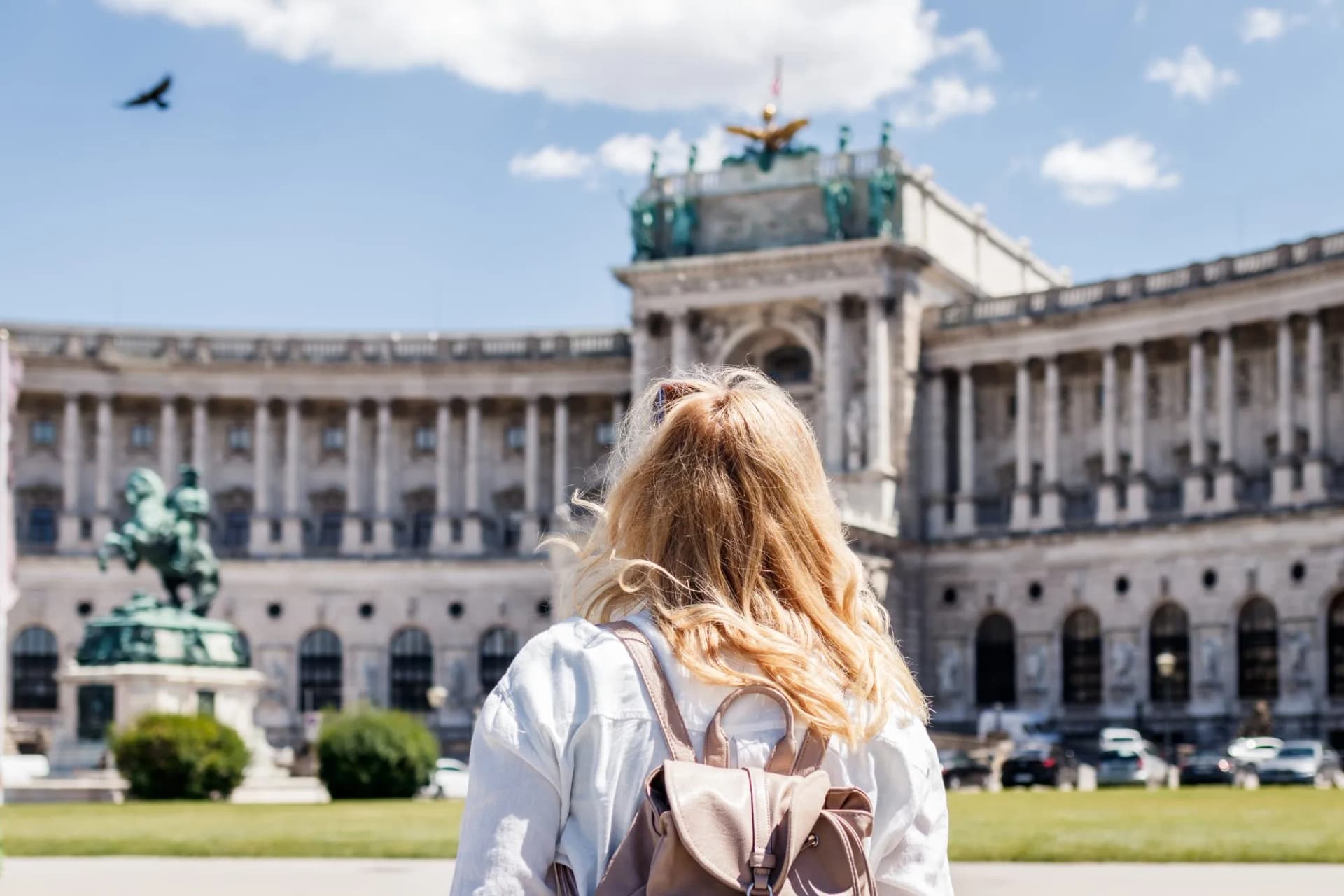 Tourist with backpack looking at Hofburg Palace in Vienna, Austria on sunny day.