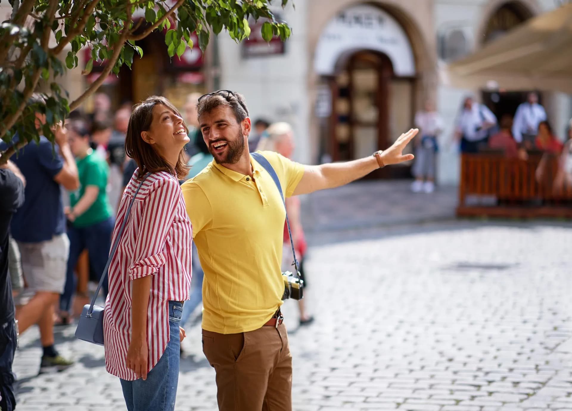 Happy couple sightseeing and smiling on a sunny European cobblestone street.