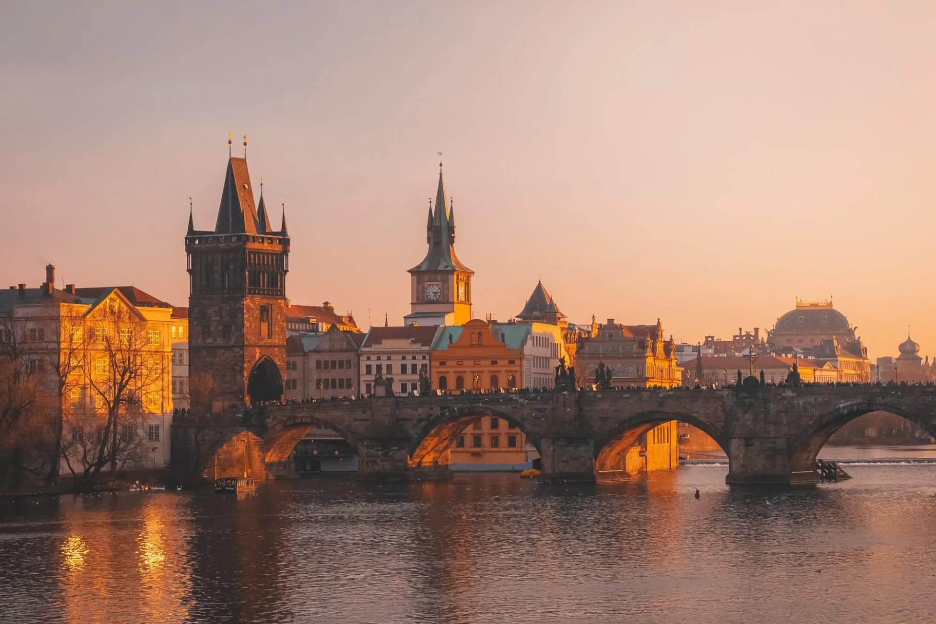 Charles Bridge over Vltava River with city skyline at Prague sunset