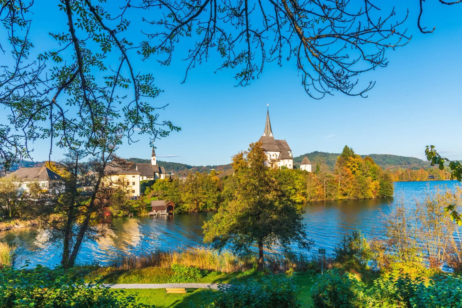 Maria Wörth church and sanctuary on Lake Wörthersee, Austria, with autumn trees.