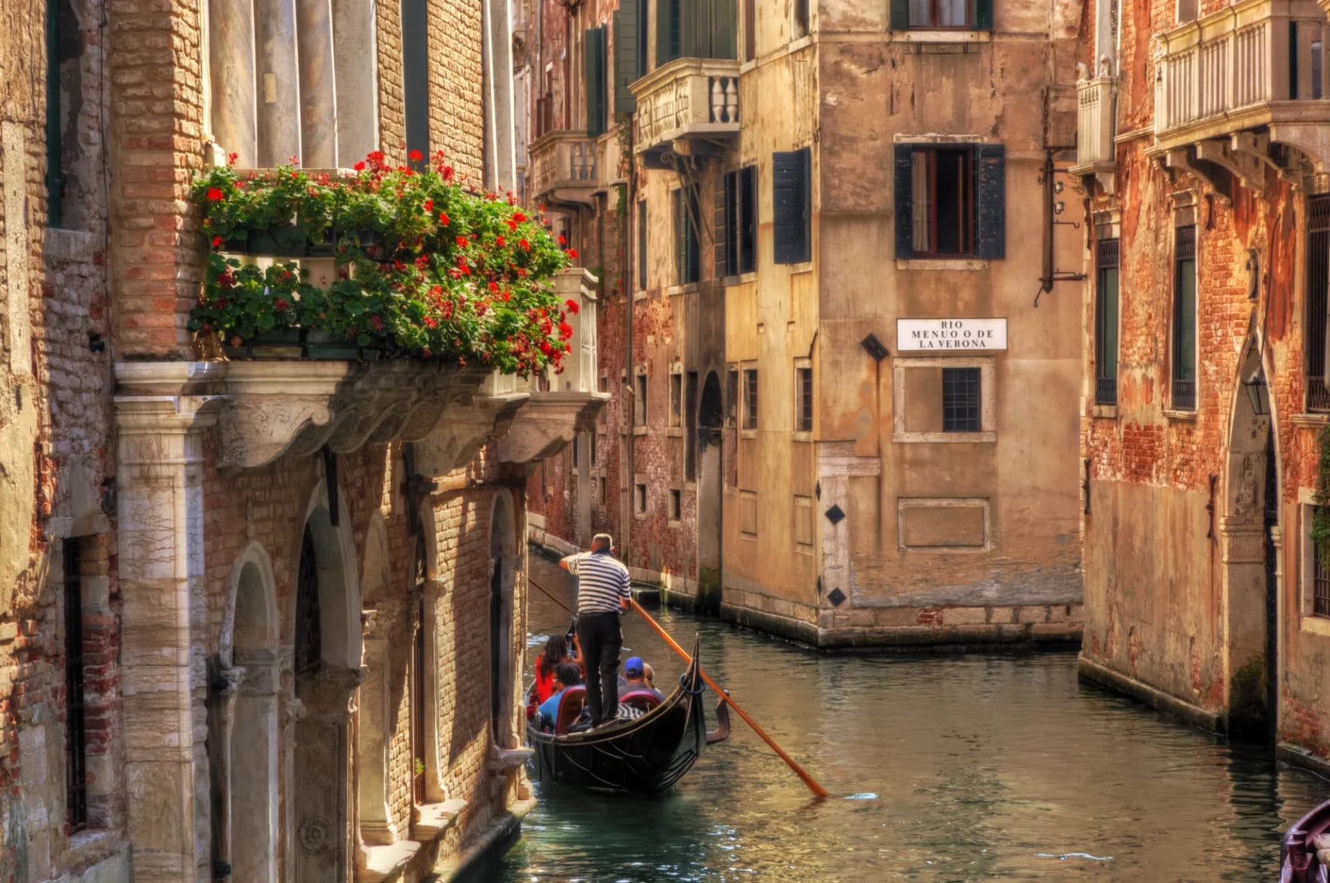 Gondola ride with gondolier on narrow canal between historic buildings in Venice, Italy